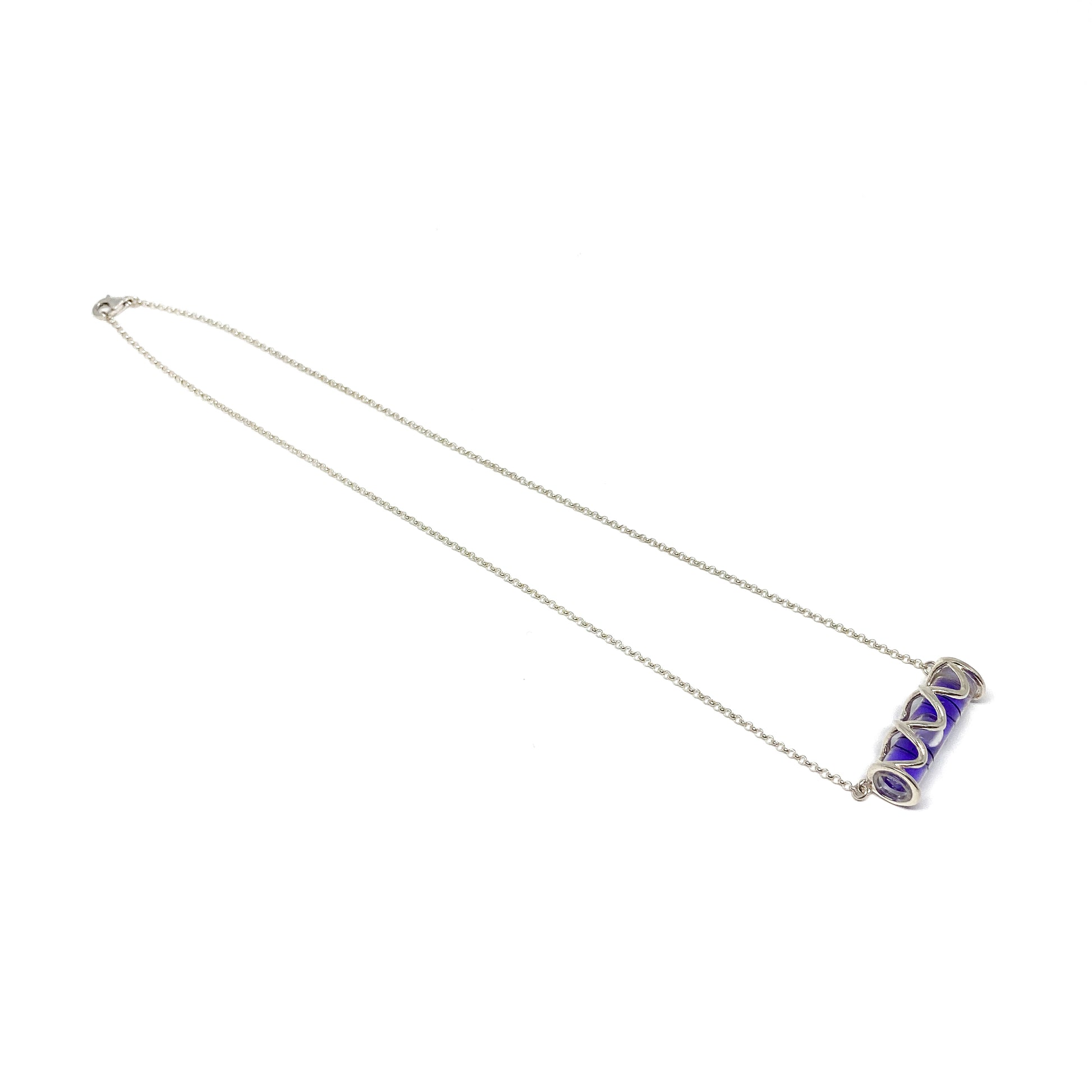 Silver necklace with a horizontal cylindrical glass pendant containing swirling vibrant purple pigment.