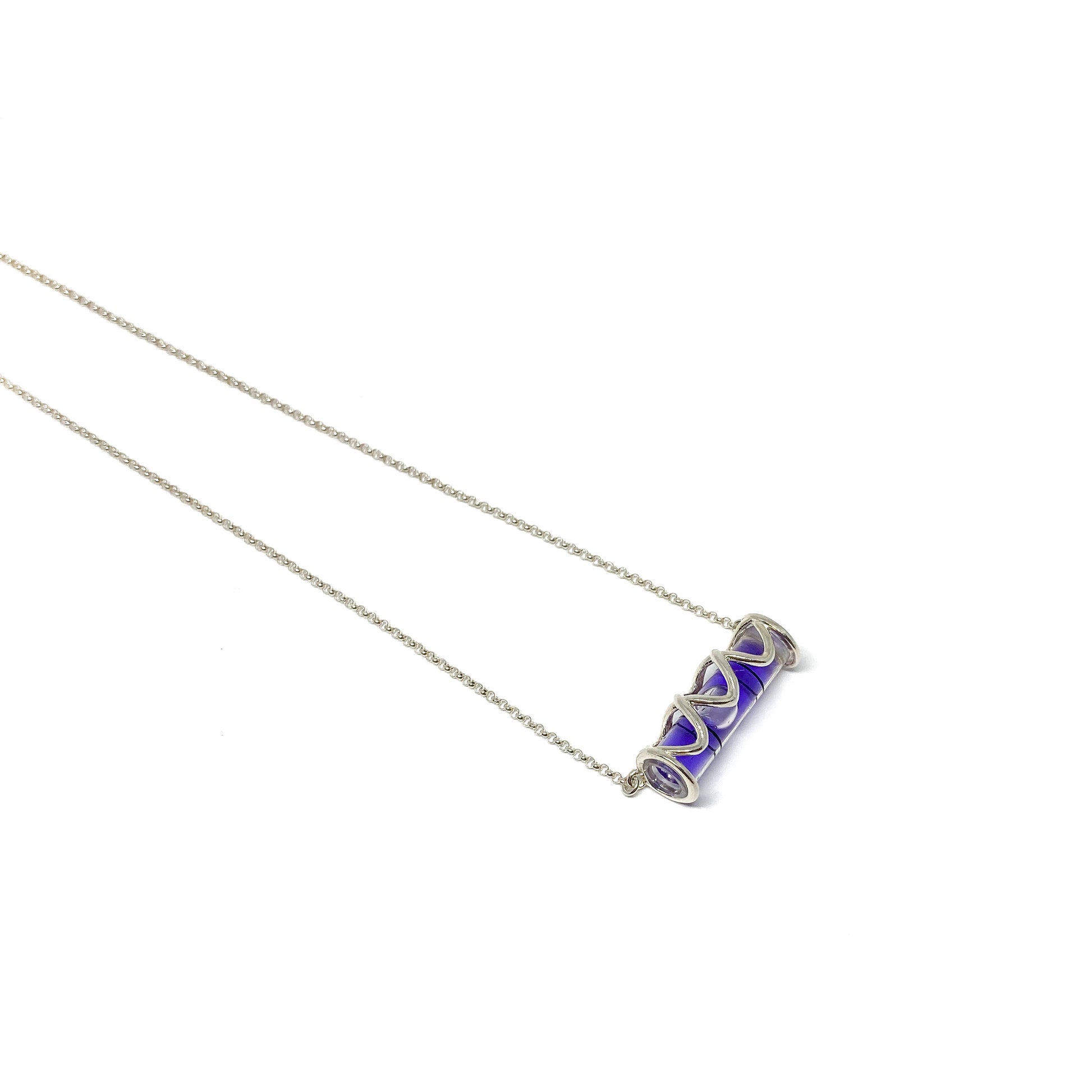 Silver necklace with a cylindrical glass pendant containing swirling vibrant purple pigment.