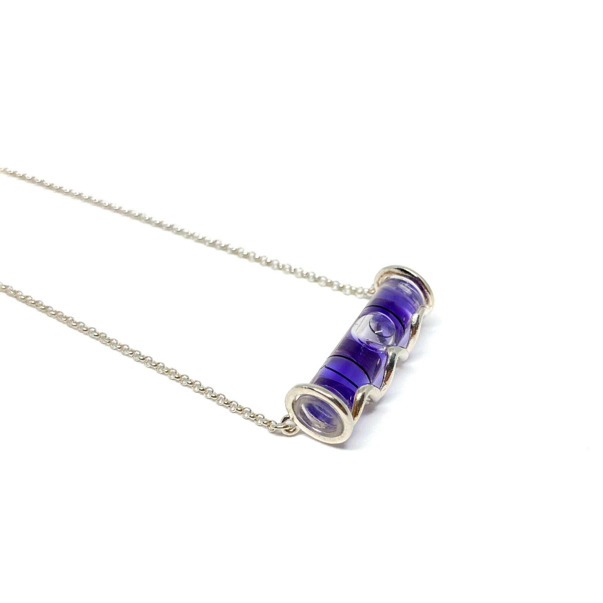 Silver necklace with a horizontal cylindrical glass pendant filled with swirling deep purple pigment and a visible air bubble.