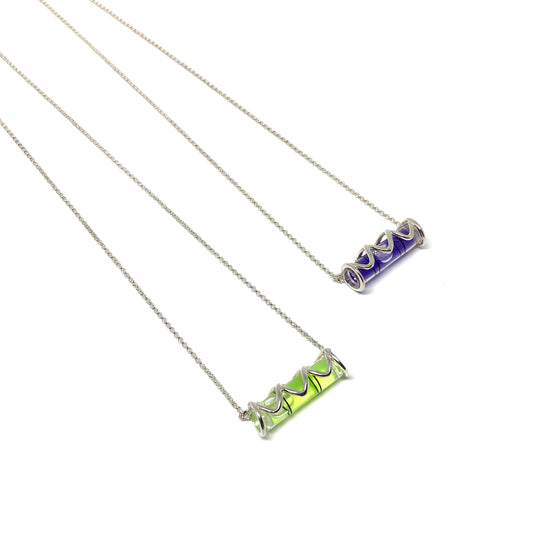 Two silver necklaces with cylindrical glass pendants containing swirling green and purple pigments.