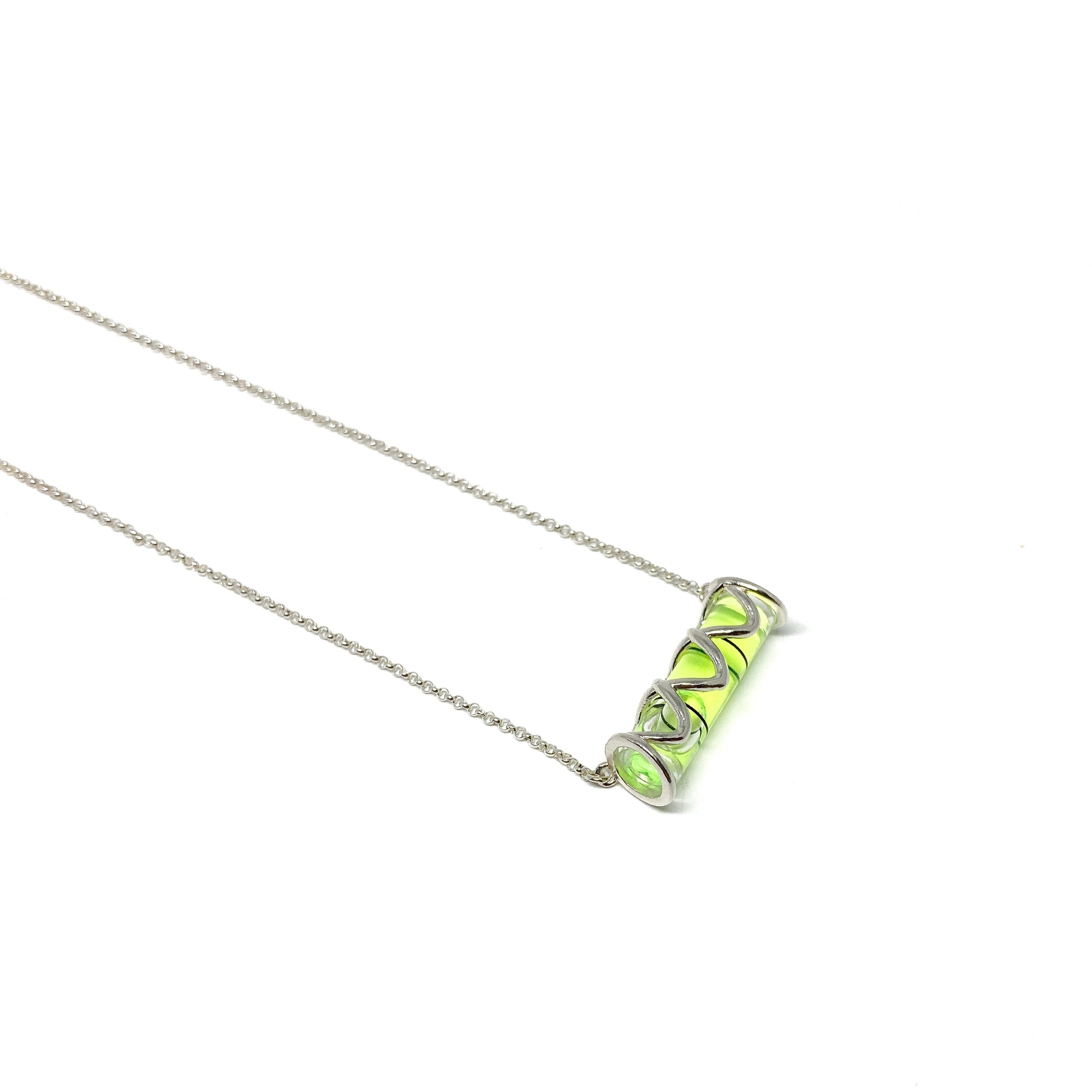 Silver necklace with a horizontal cylindrical glass pendant containing swirling vibrant lime green pigment.