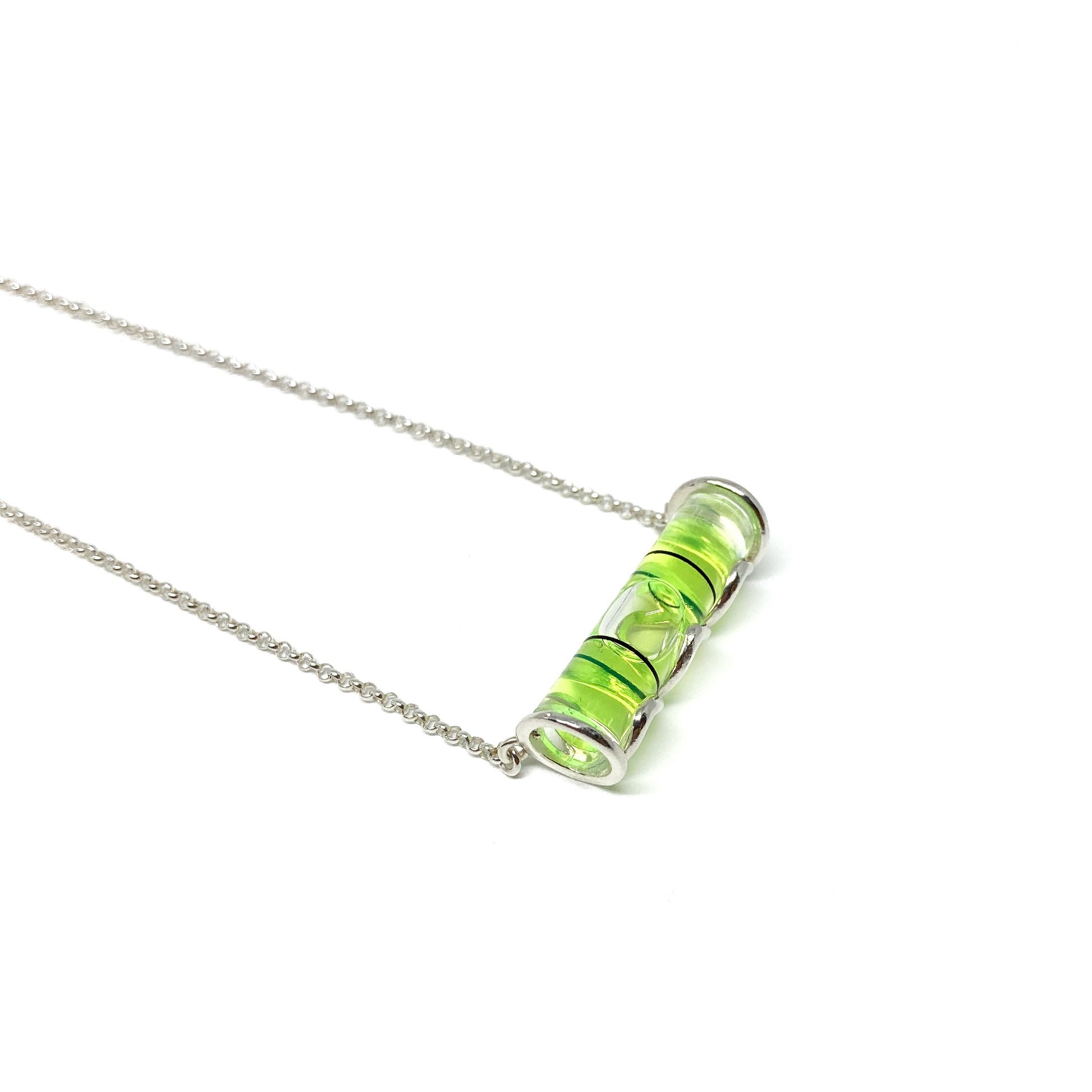 Silver necklace with a horizontal cylindrical glass pendant filled with swirling bright green pigment and a visible air bubble.