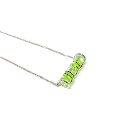 Silver necklace with a horizontal cylindrical glass pendant filled with swirling bright green pigment and a visible air bubble.