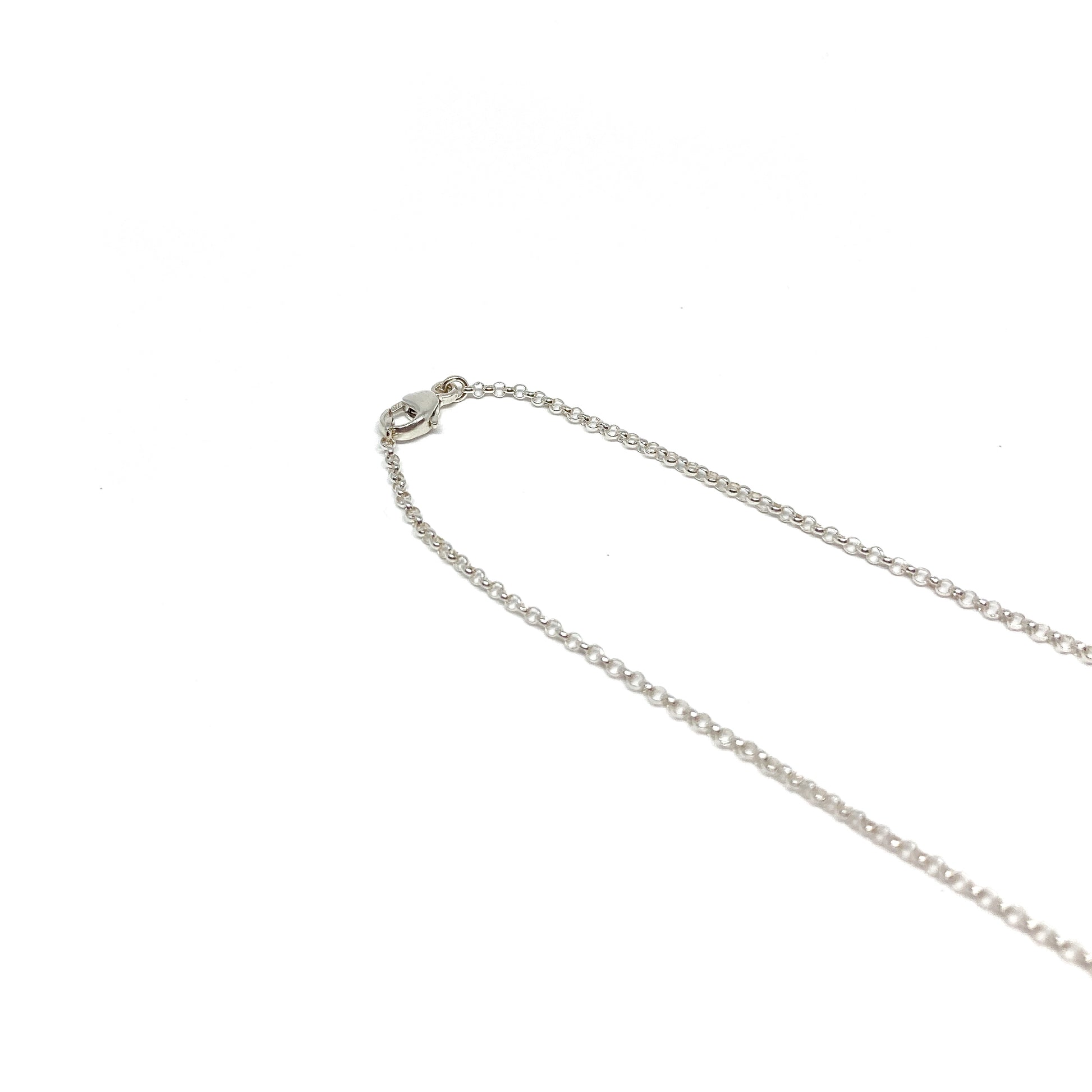 A close-up of a fine silver chain necklace with a small lobster clasp at the top left.