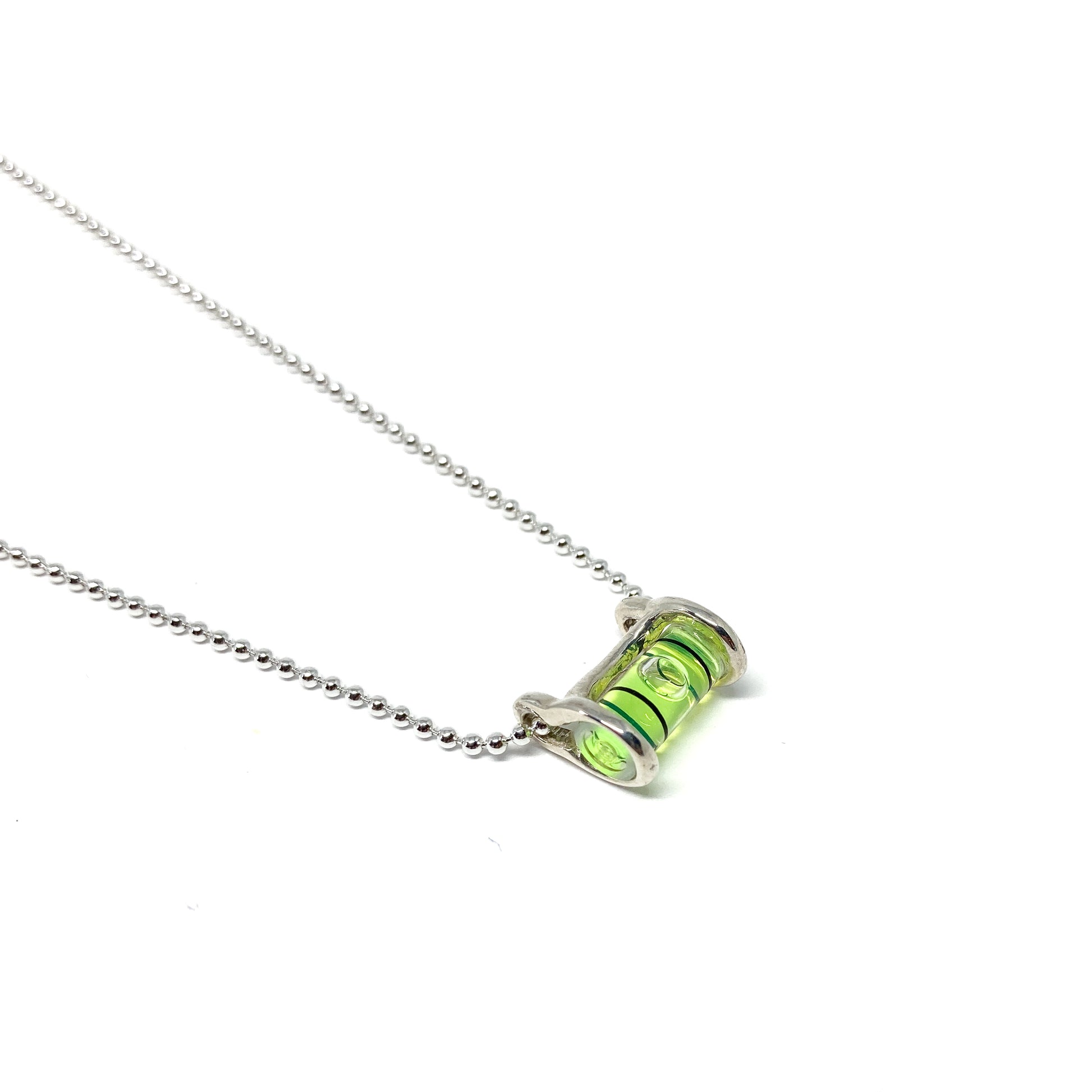 Silver necklace with a horizontal cylindrical glass pendant filled with swirling bright green pigment and a visible air bubble.