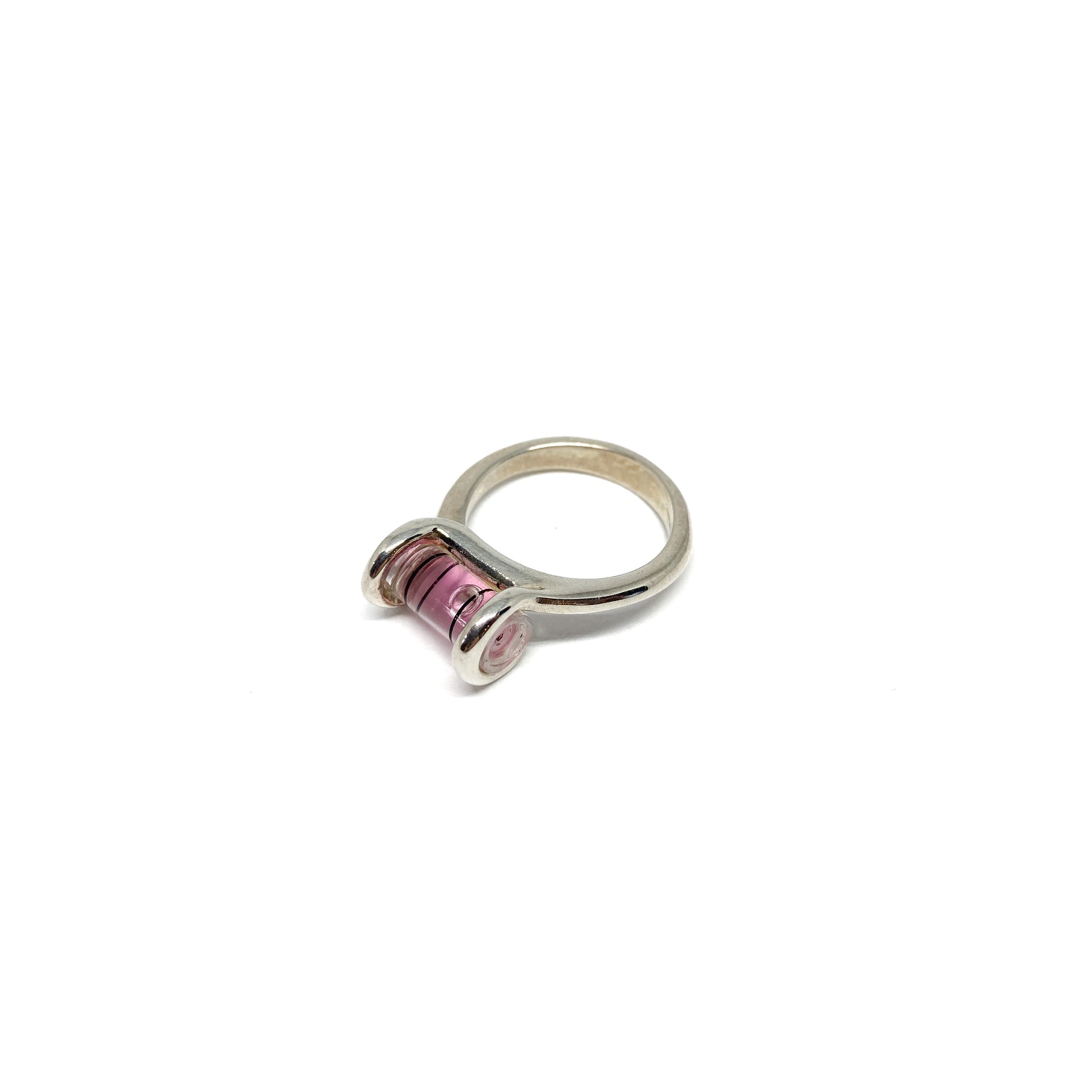 Silver ring featuring a miniature bubble level with pink liquid and a centered clear bubble.