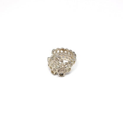 A shiny silver ring shaped like a honeycomb wraps around, featuring a detailed bee on one cell.