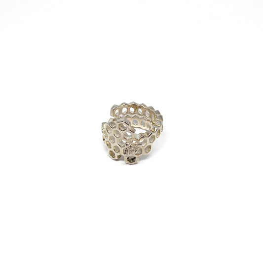 A shiny silver ring shaped like a honeycomb wraps around, featuring a detailed bee on one cell.
