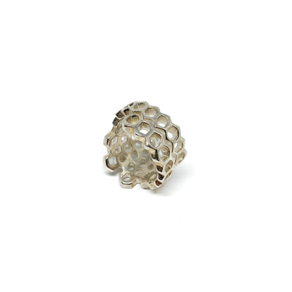 A shiny silver ring with an openwork honeycomb design is shown in a close-up view.