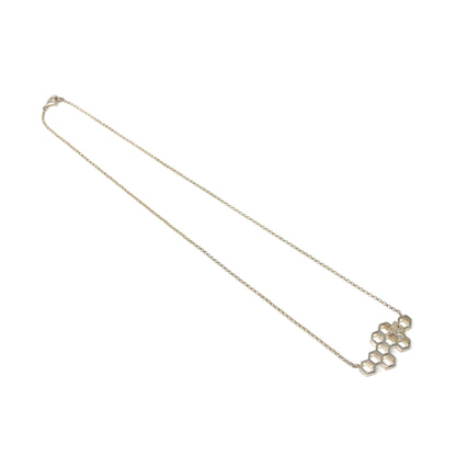 A long, delicate silver chain leads to a honeycomb pendant with a bee detail at the bottom right.