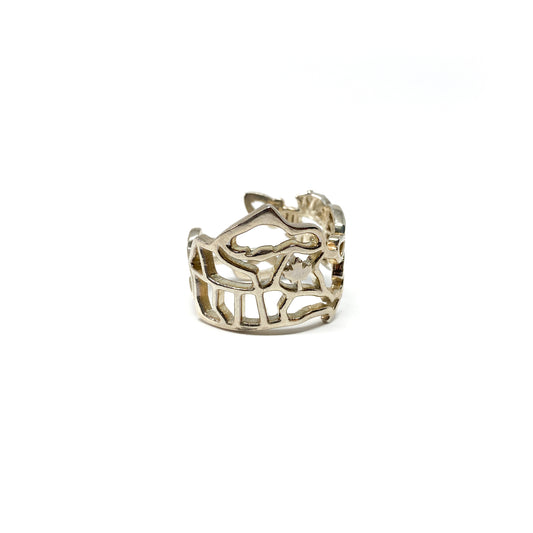 A shiny silver ring with a detailed cut-out design of the map of Canada, including a maple leaf, is shown.