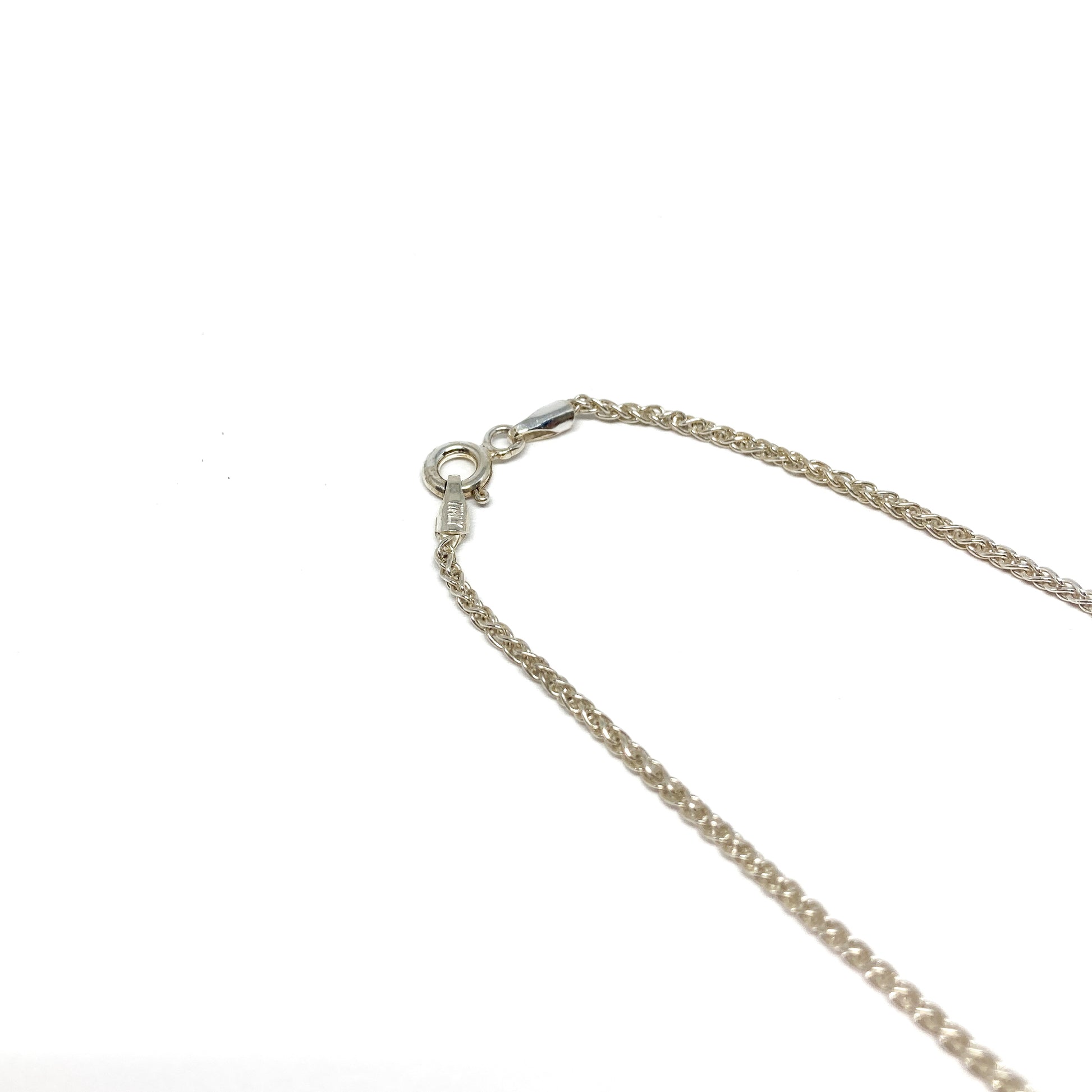 A close-up shows the lobster clasp and the fine, twisted links of a silver necklace chain.