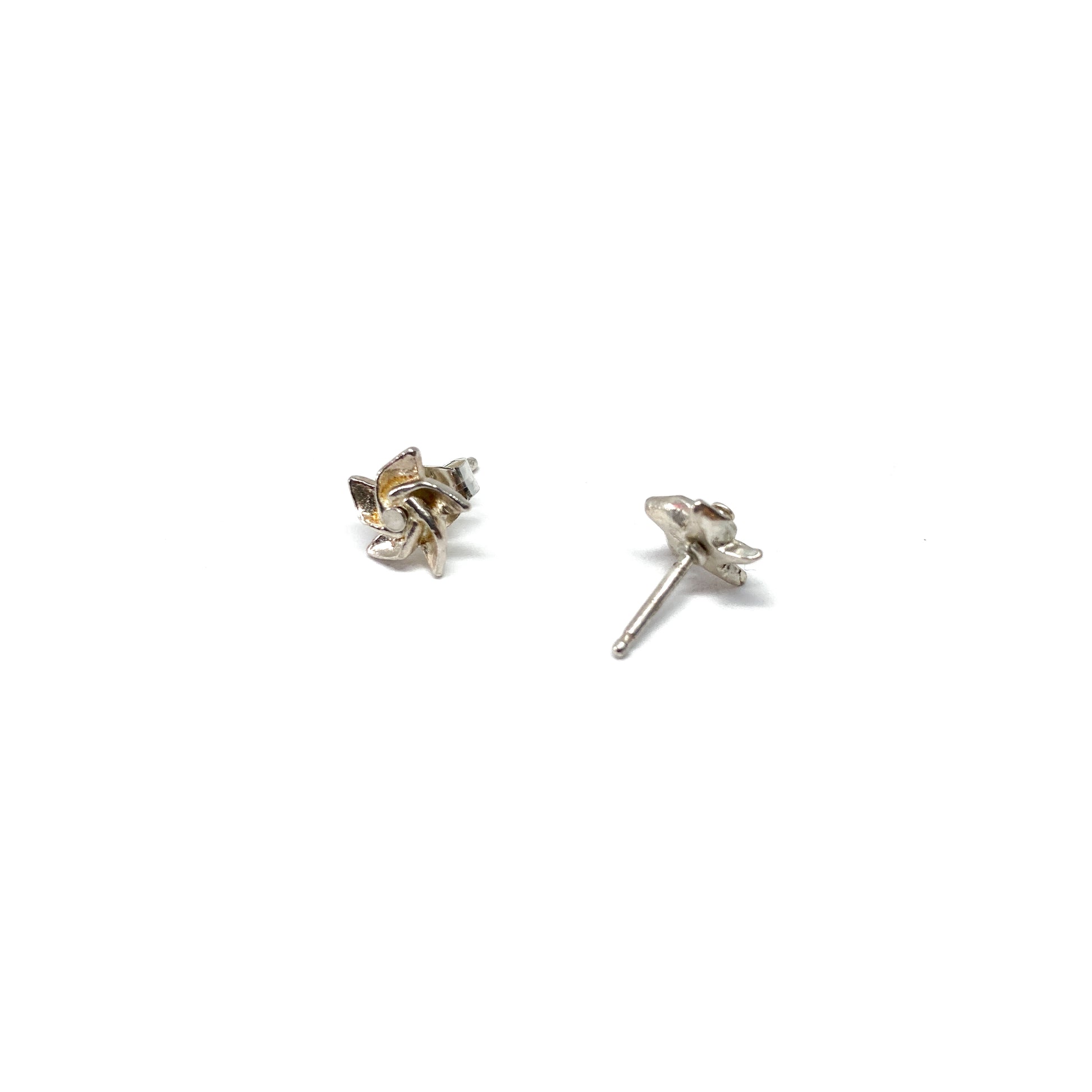 Two shiny silver stud earrings, one showing the post, are shaped like stylized three-pronged designs.