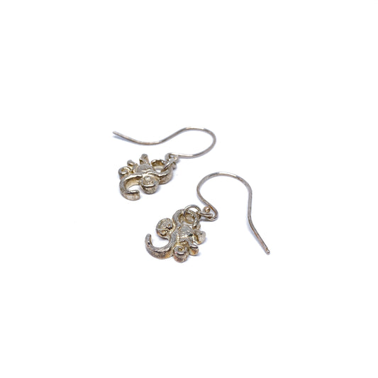 Two shiny silver dangle earrings with a textured, abstract floral or organic design on fishhook wires are shown.