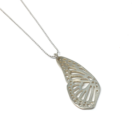 A silver ball chain necklace features a delicate, openwork pendant shaped like a monarch butterfly wing.