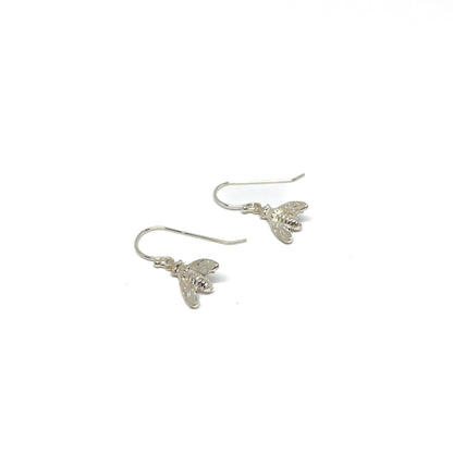 Two shiny silver dangle earrings, each shaped like a detailed bee, hang from delicate fishhook wires.