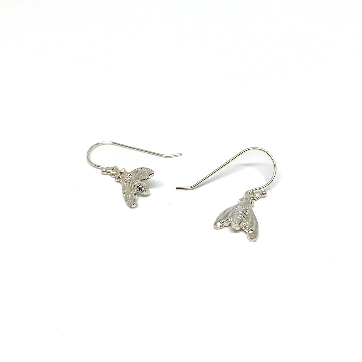 Two shiny silver dangle earrings, each shaped like a detailed bumblebee, hang from fishhook wires.