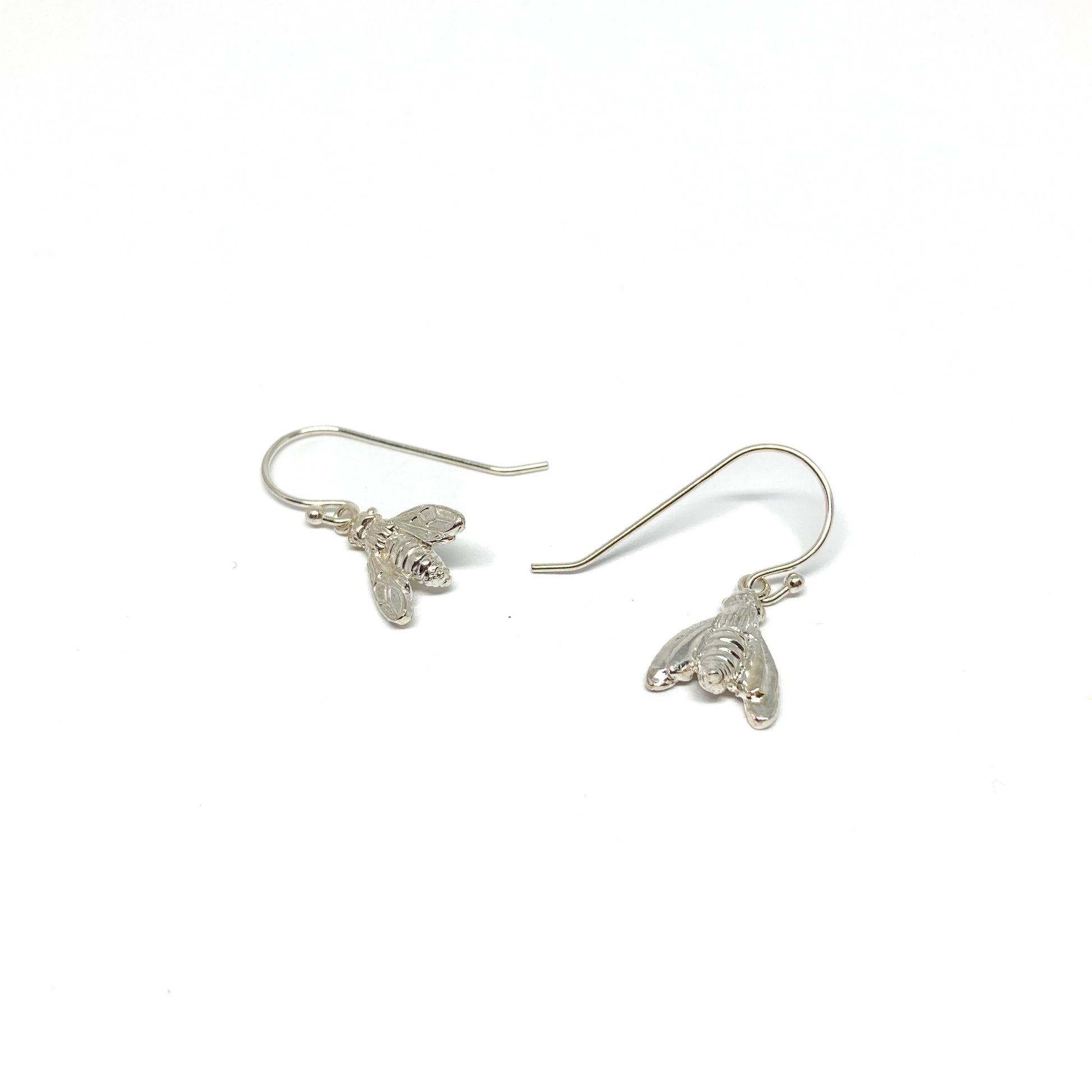 Two shiny silver dangle earrings, each shaped like a detailed bumblebee, hang from fishhook wires.