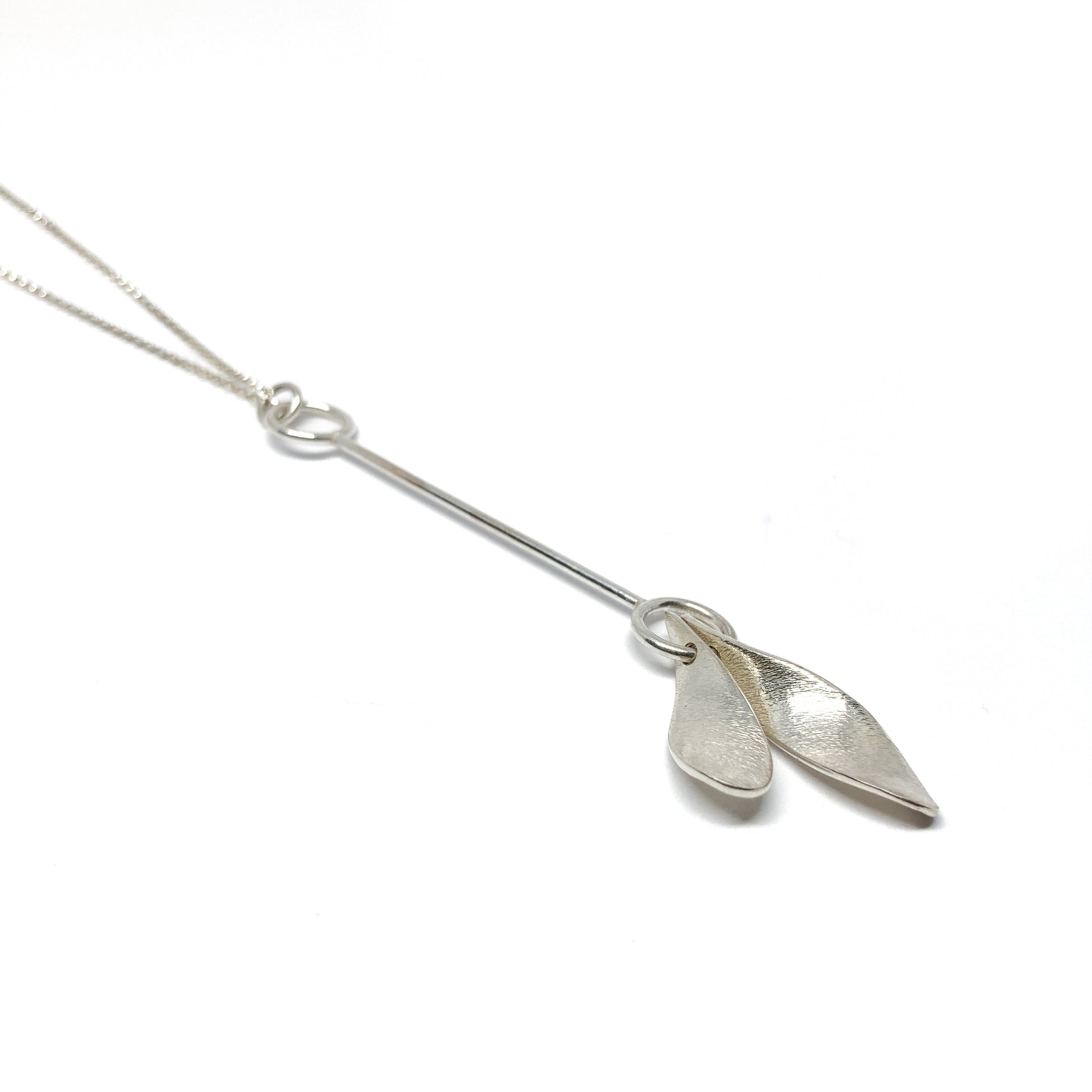 Silver necklace with two leaf-shaped pendants, close-up view.