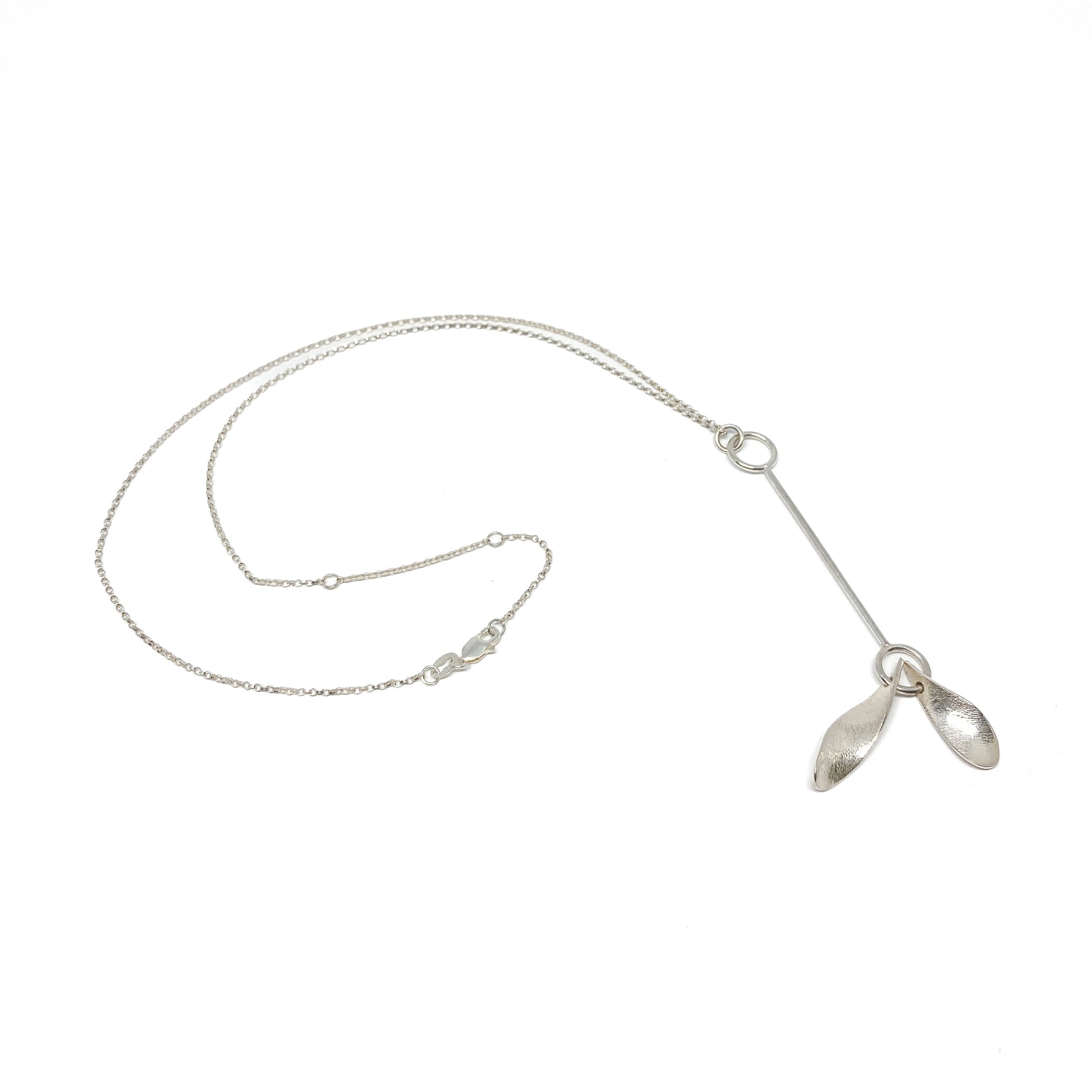 Silver necklace with leaf pendants, chain detail visible, angled.