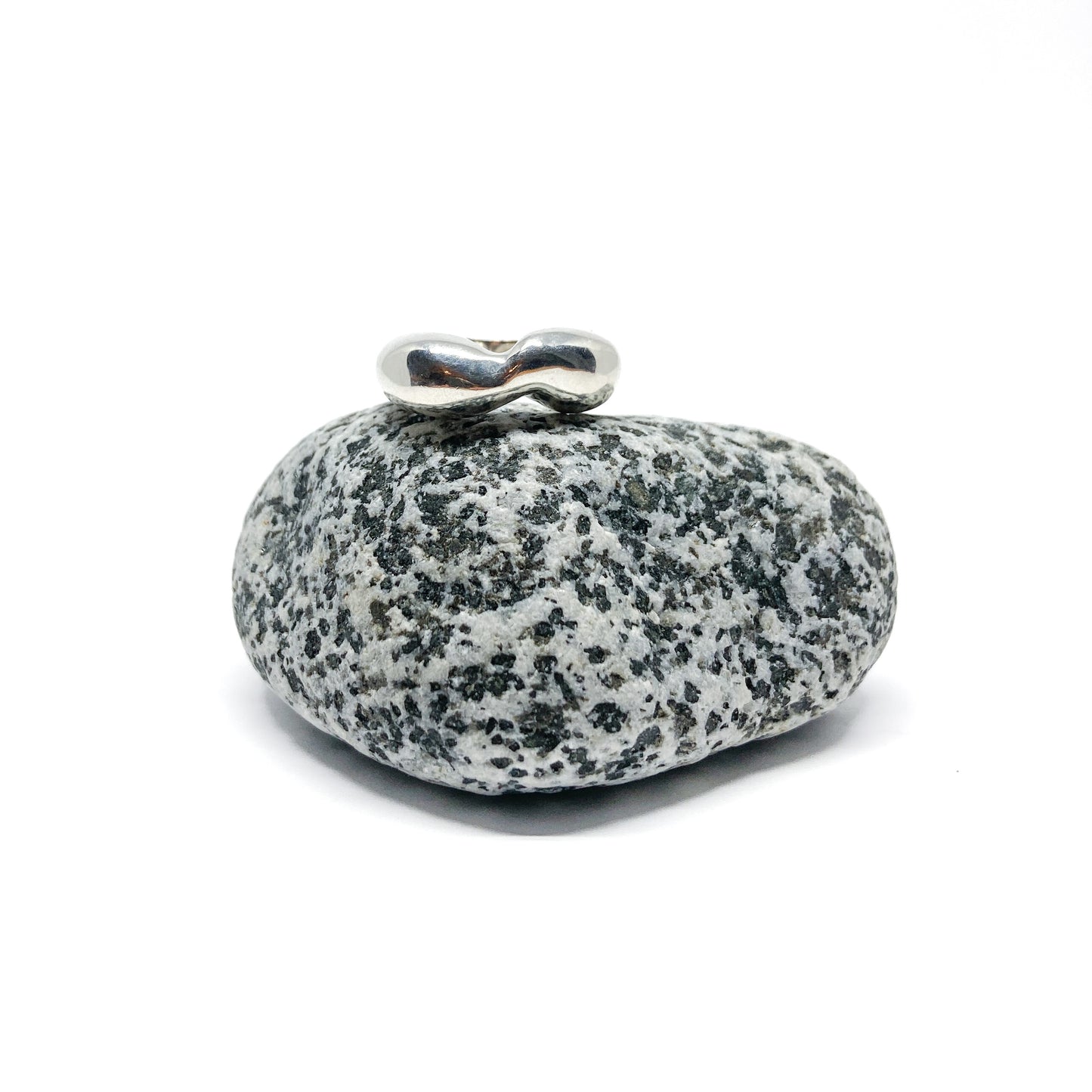 Silver ring on speckled gray stone.
