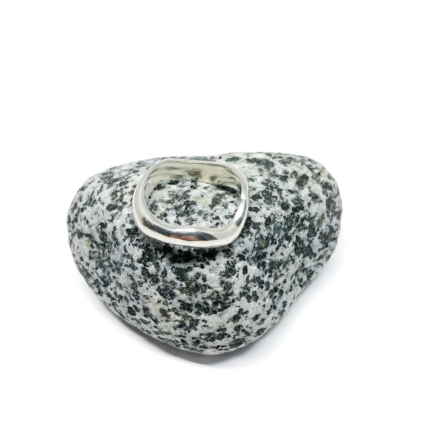 Silver ring on a textured gray stone, close-up.
