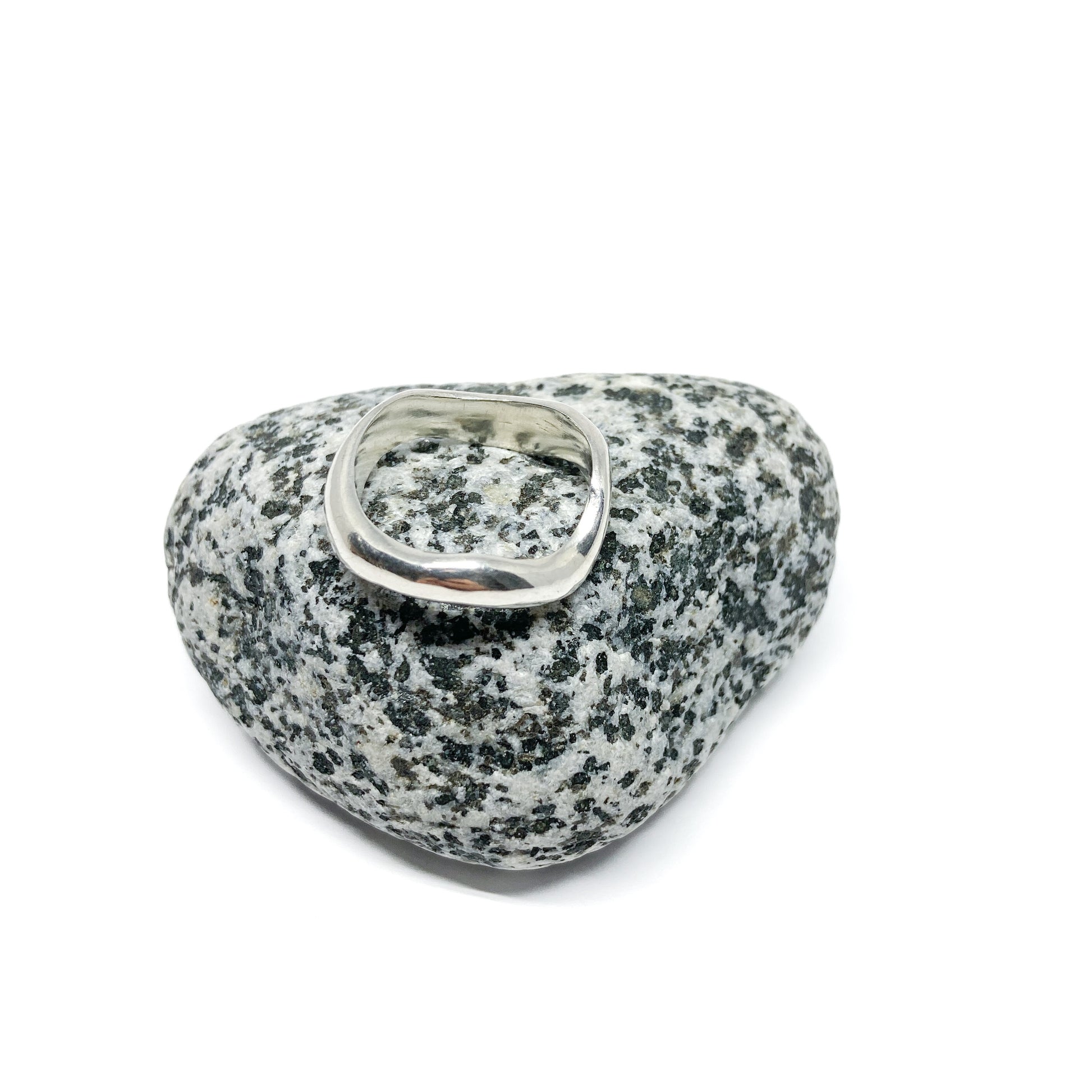 Silver ring on a textured gray stone, close-up.