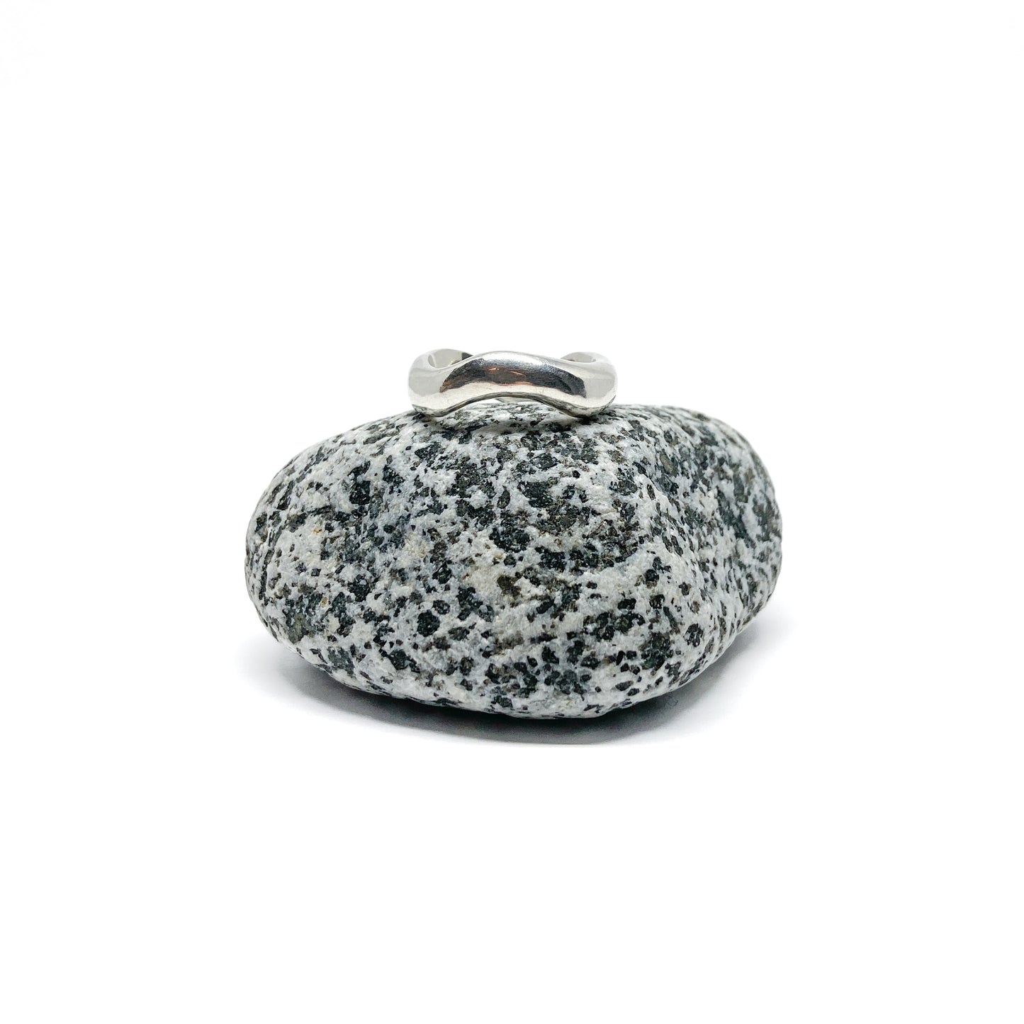Silver ring on a textured gray stone, close-up.