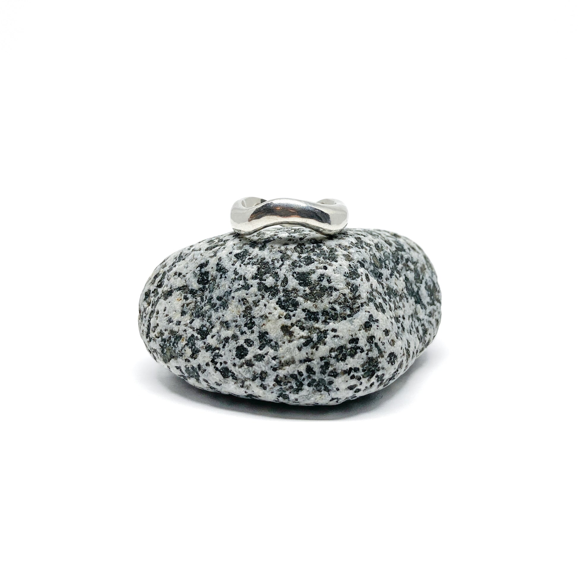 Silver ring on a textured gray stone, close-up.