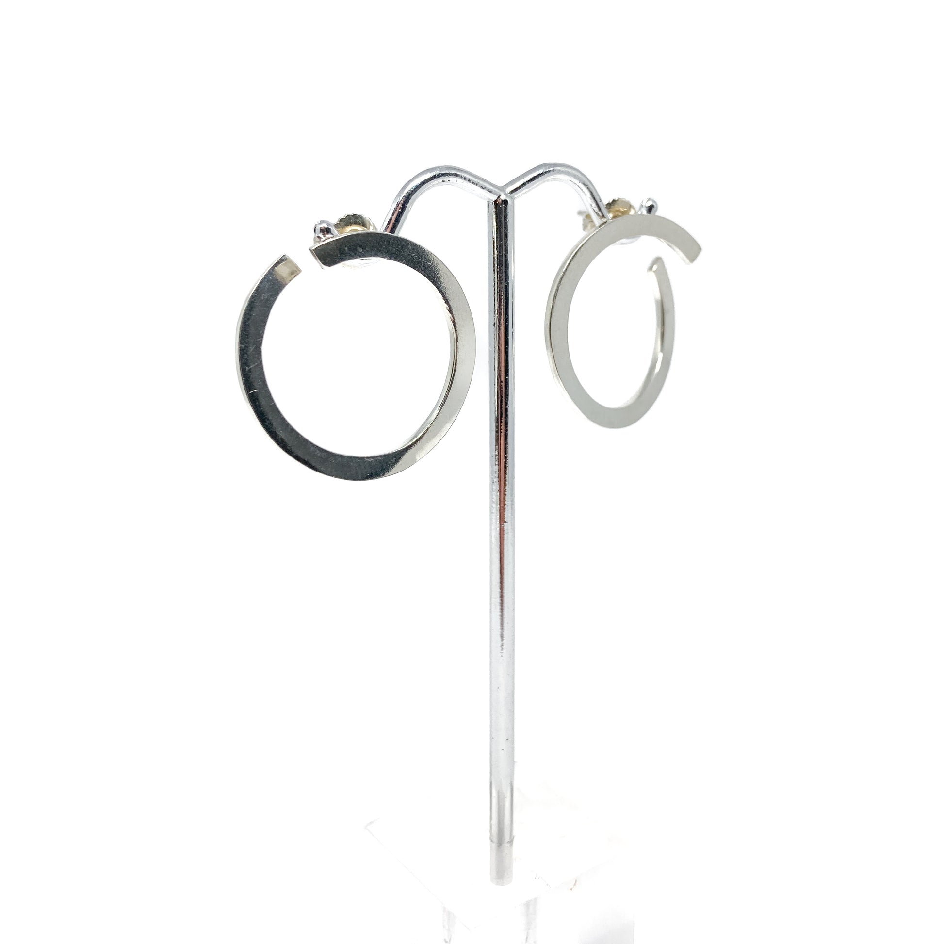 Silver open hoop earrings on a stand, front view.