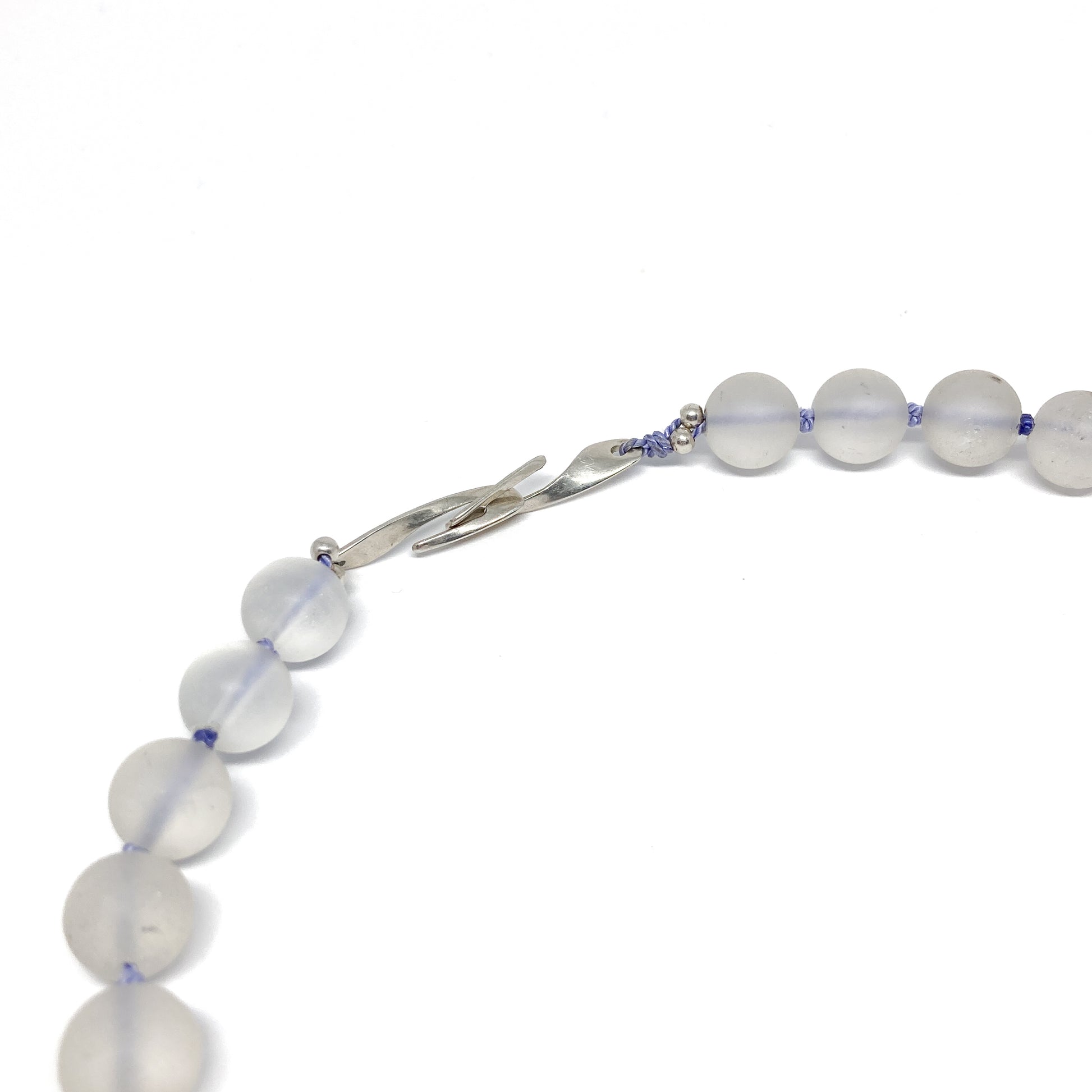 Clear quartz necklace with silver clasp, close-up.