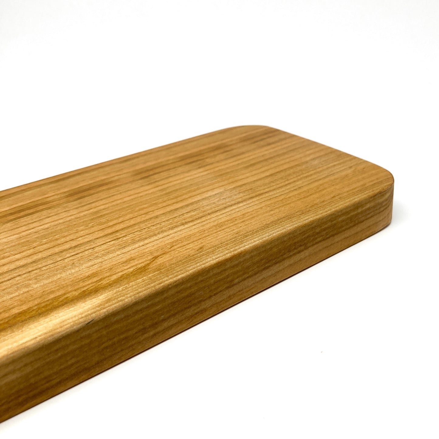 Close-up of the smooth, rounded edge of a wooden charcuterie board.