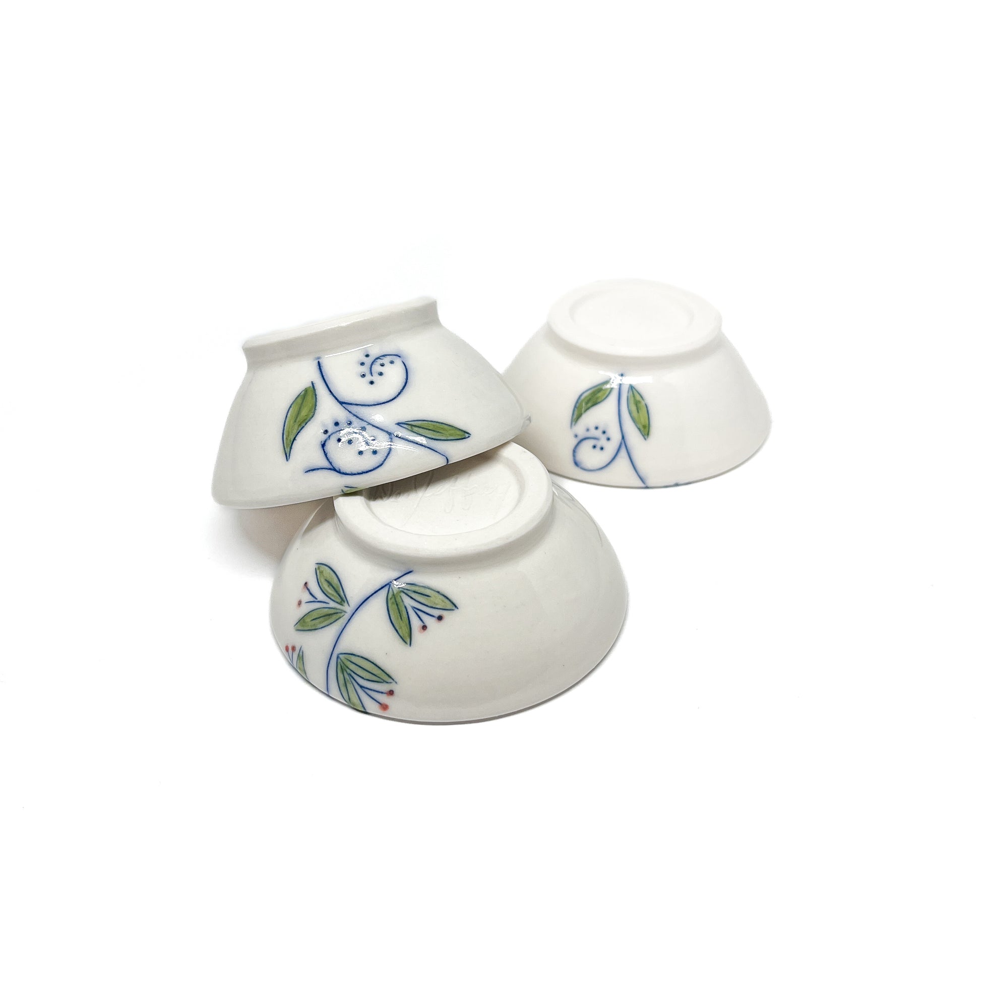 Three small ceramic dishes stacked, each with blue swirls and green and red leaf designs.