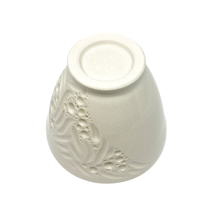 Underside view of a small ceramic bowl with textured floral and bubble designs.