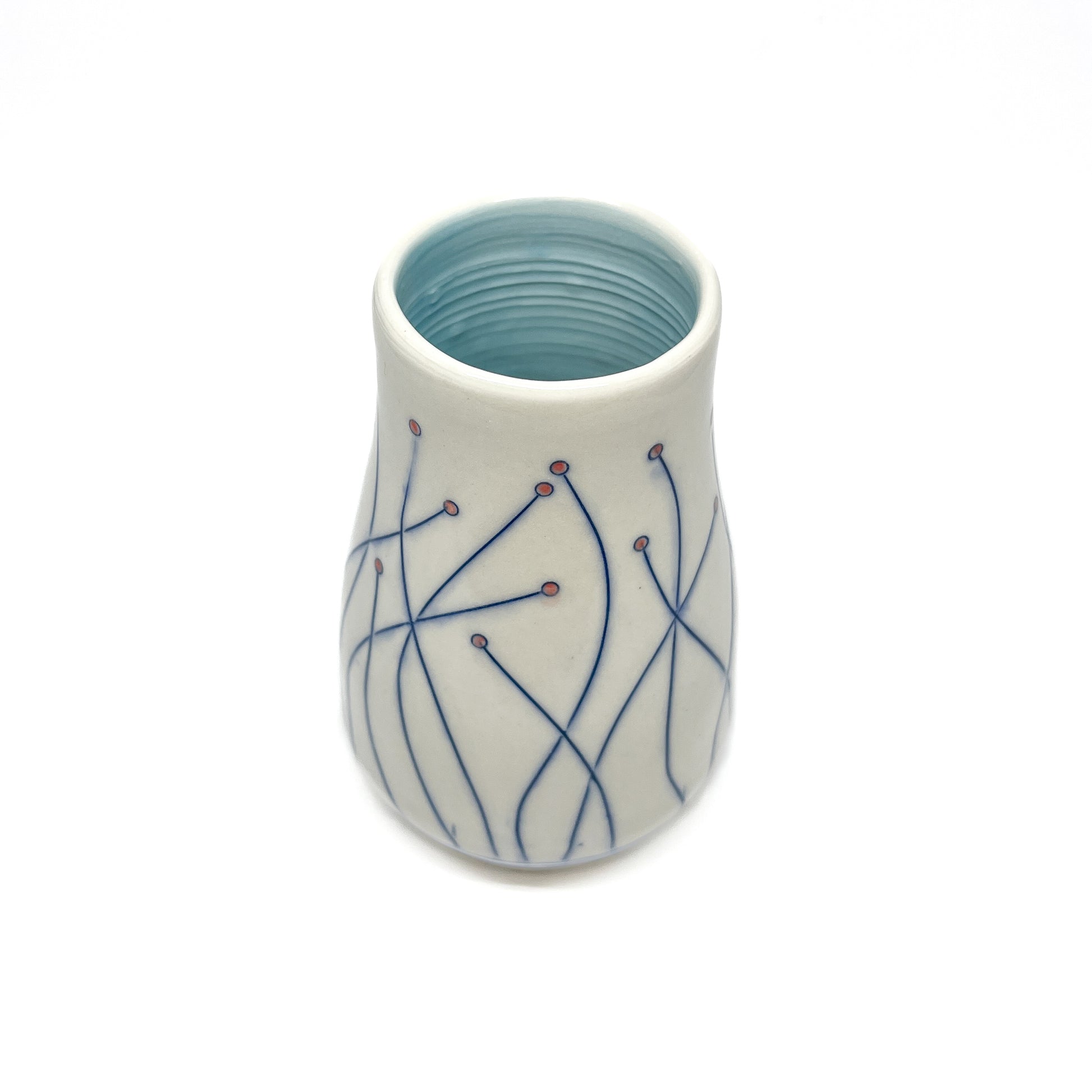 A white ceramic vase with a light blue inner glaze features blue line drawings of stems with small red circular details.