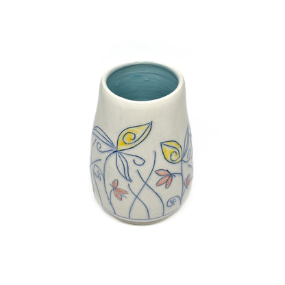 A white ceramic vase with a light blue inner glaze is decorated with blue outlined flowers and stems with yellow and reddish-orange petal accents.