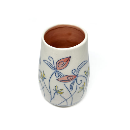 A white ceramic vase with a light brown inner glaze features blue outlined flowers and stems with reddish-orange and yellow petal accents.