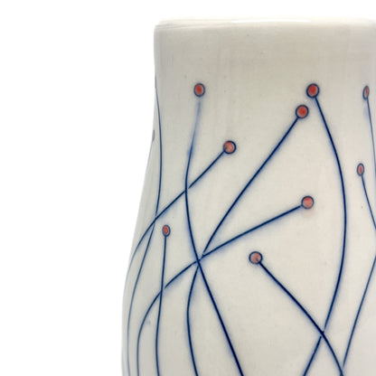 Close-up of a white ceramic vase with blue line drawings of stems ending in small red circular details.
