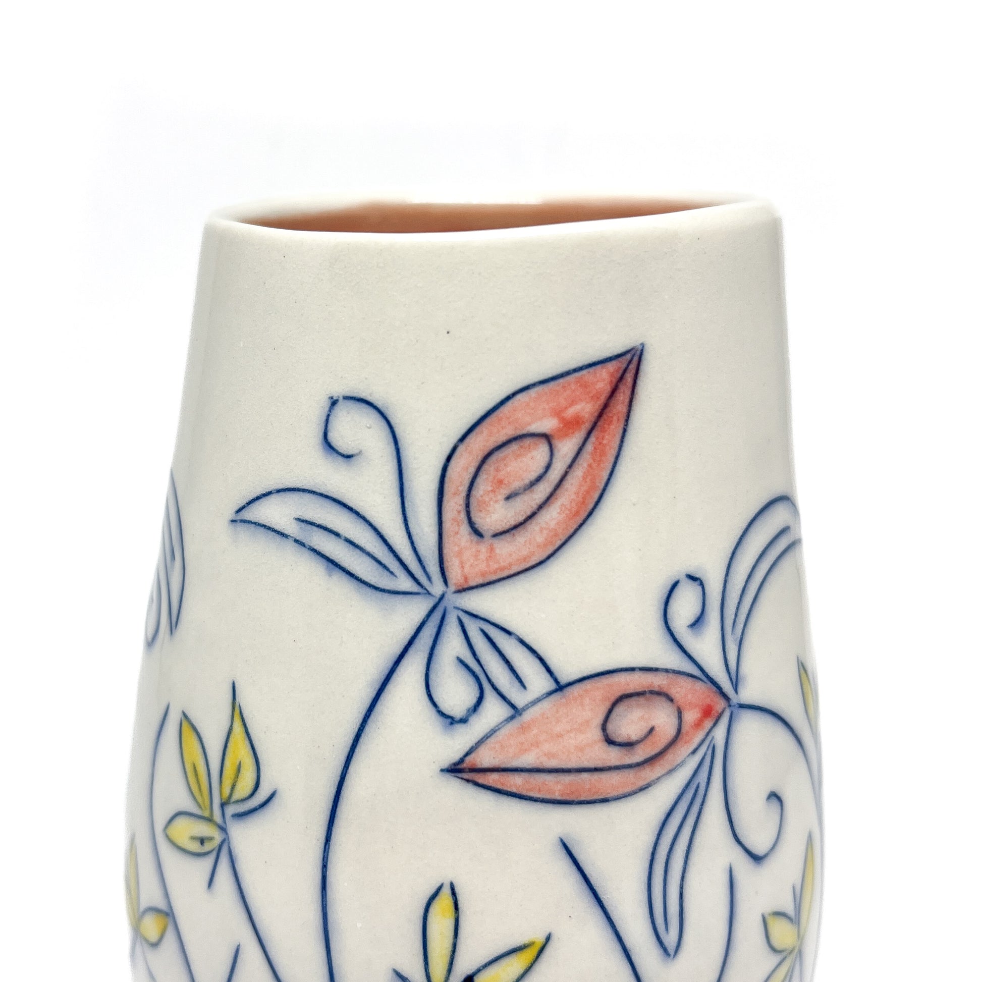 Close-up of a white ceramic vase showing blue outlined floral designs with reddish-orange and yellow petal details. The inner glaze is light brown.