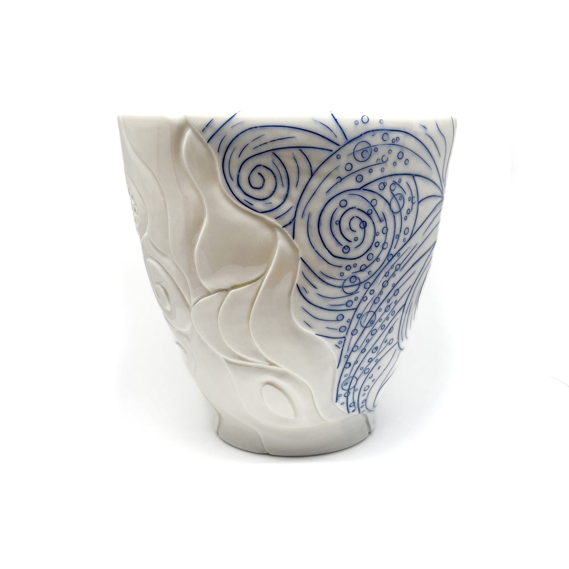 Handmade pottery bowl with carved white abstract shapes contrasting with blue swirling lines and dot patterns.