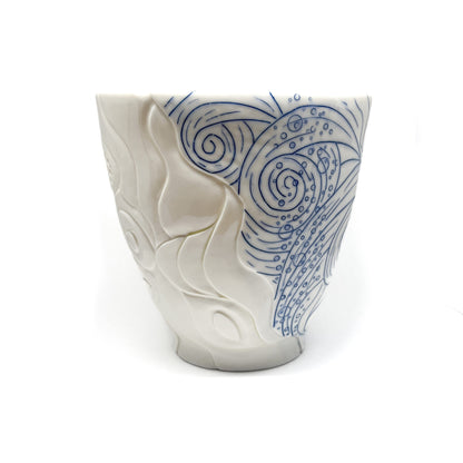 Handmade pottery bowl with carved white abstract shapes contrasting with blue swirling lines and dot patterns.