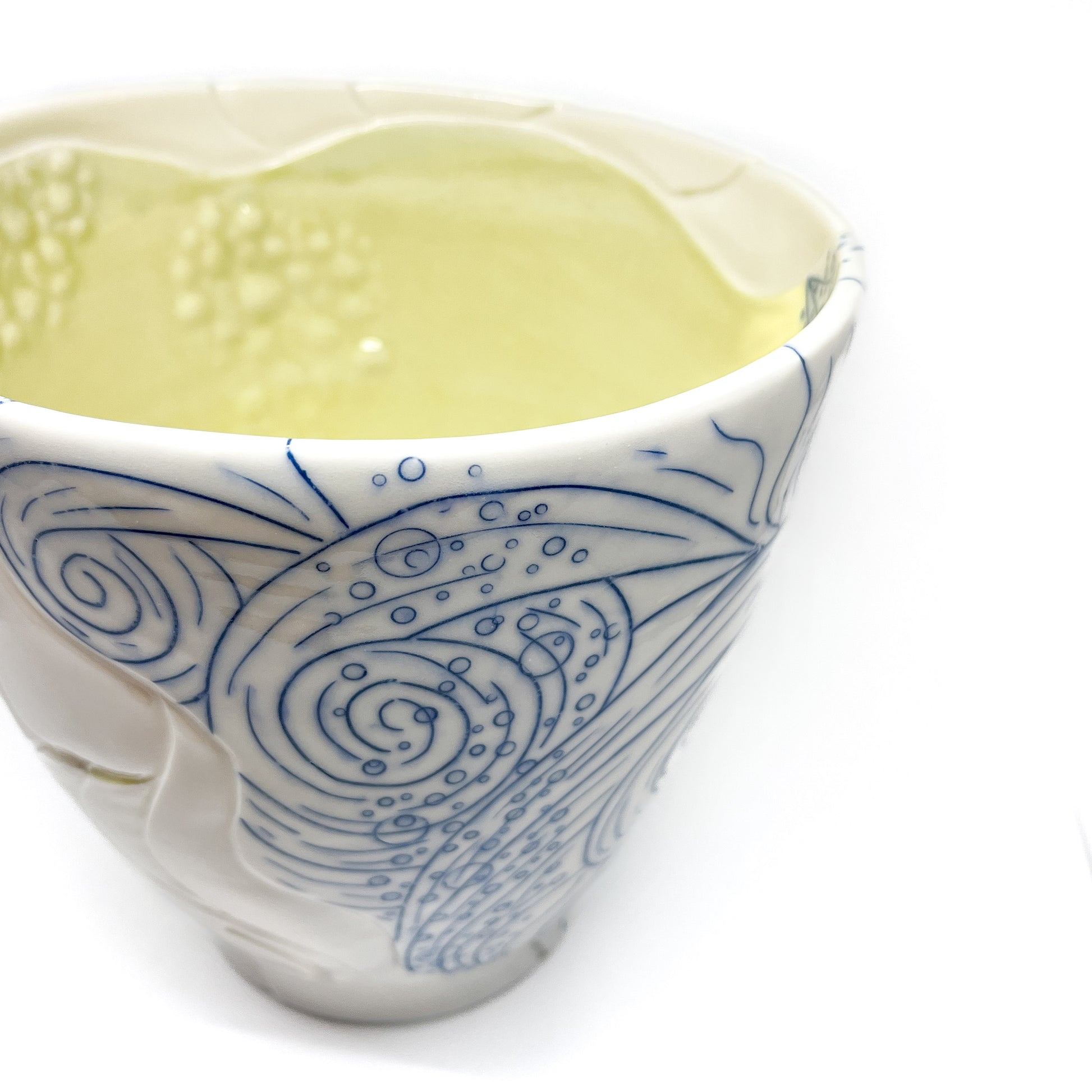 Close-up of a small ceramic bowl with abstract blue line art and textured white swirls.