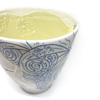 Close-up of a small ceramic bowl with abstract blue line art and textured white swirls.