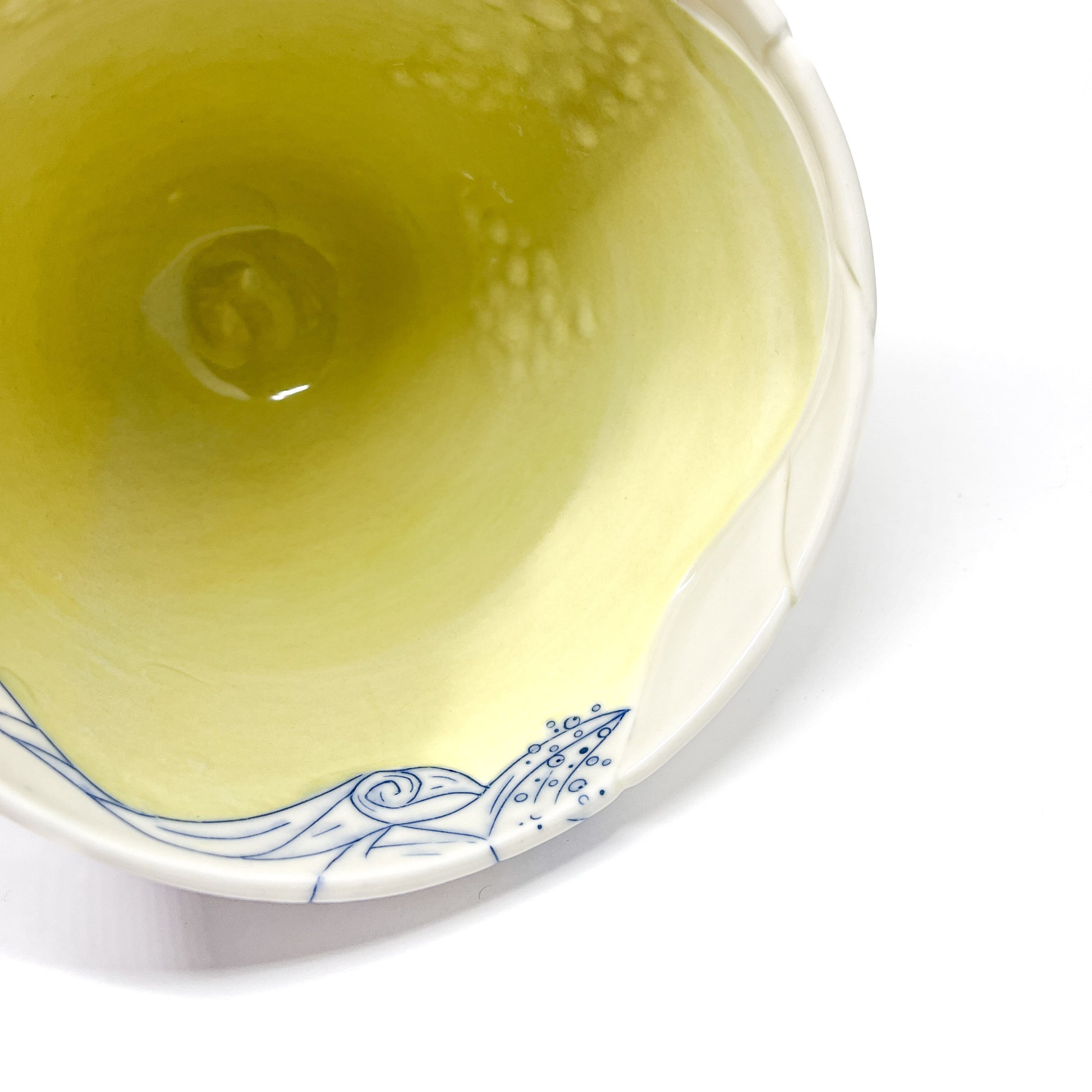 Partial top view of a ceramic bowl with a smooth interior and blue abstract designs on the rim.