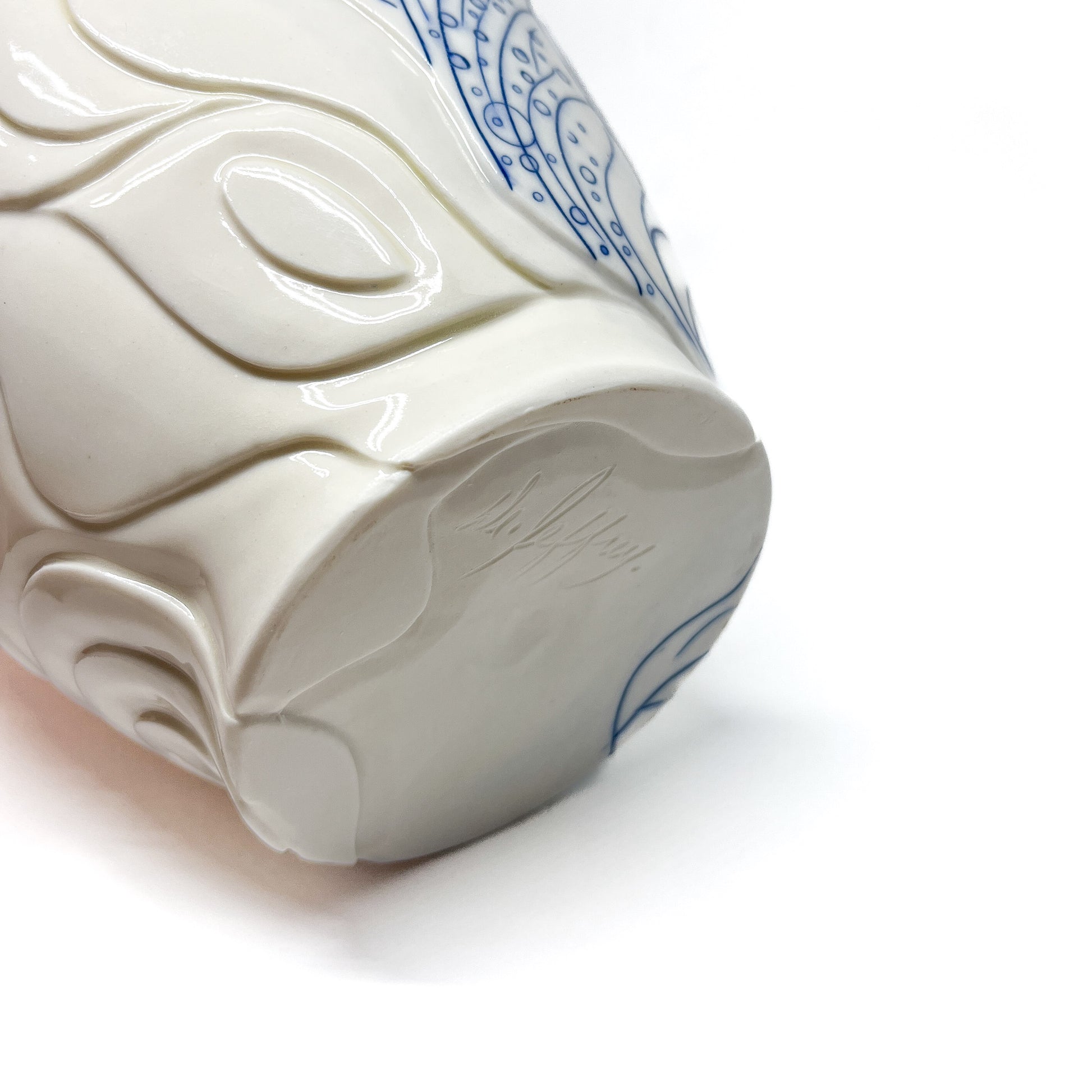 Base of a small ceramic bowl showing textured swirl designs, blue abstract art, and a signature.