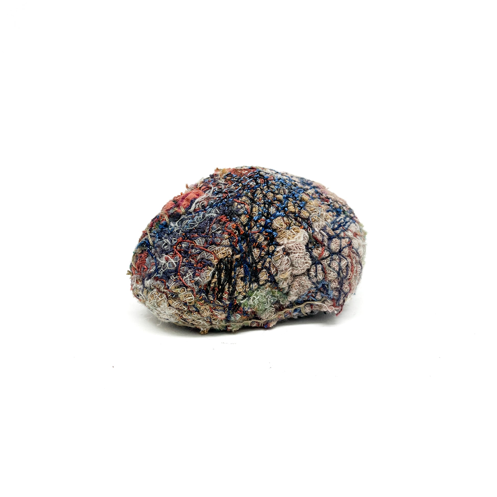 Embroidered Rock by Jane Kenyon: Round textured textile art resembling a rock, with dense stitching in blue, red, white, and tan threads.