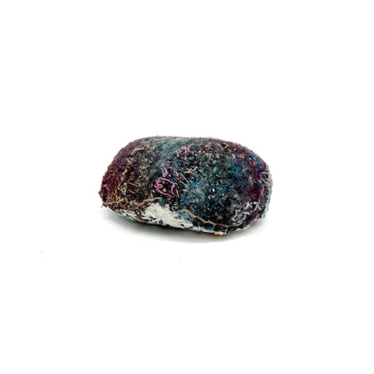 Embroidered Rock by Jane Kenyon: Oval textured textile art resembling a rock, with layered stitching in purple, blue, white, and gold threads.