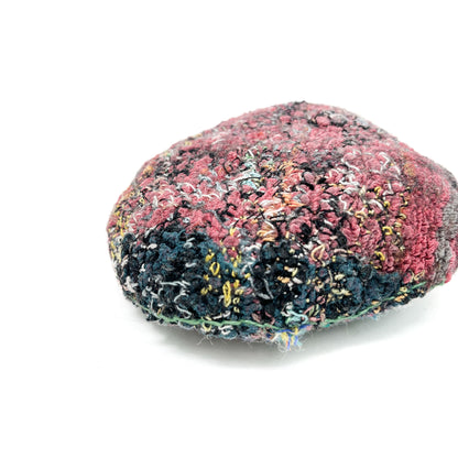 Embroidered Rock: Round textured textile art resembling a rock, with layered stitching in pink, black, blue, and yellow threads.