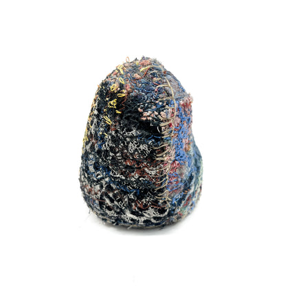An embroidered rock, showcasing intricate stitched textures and a blend of diverse colored threads.