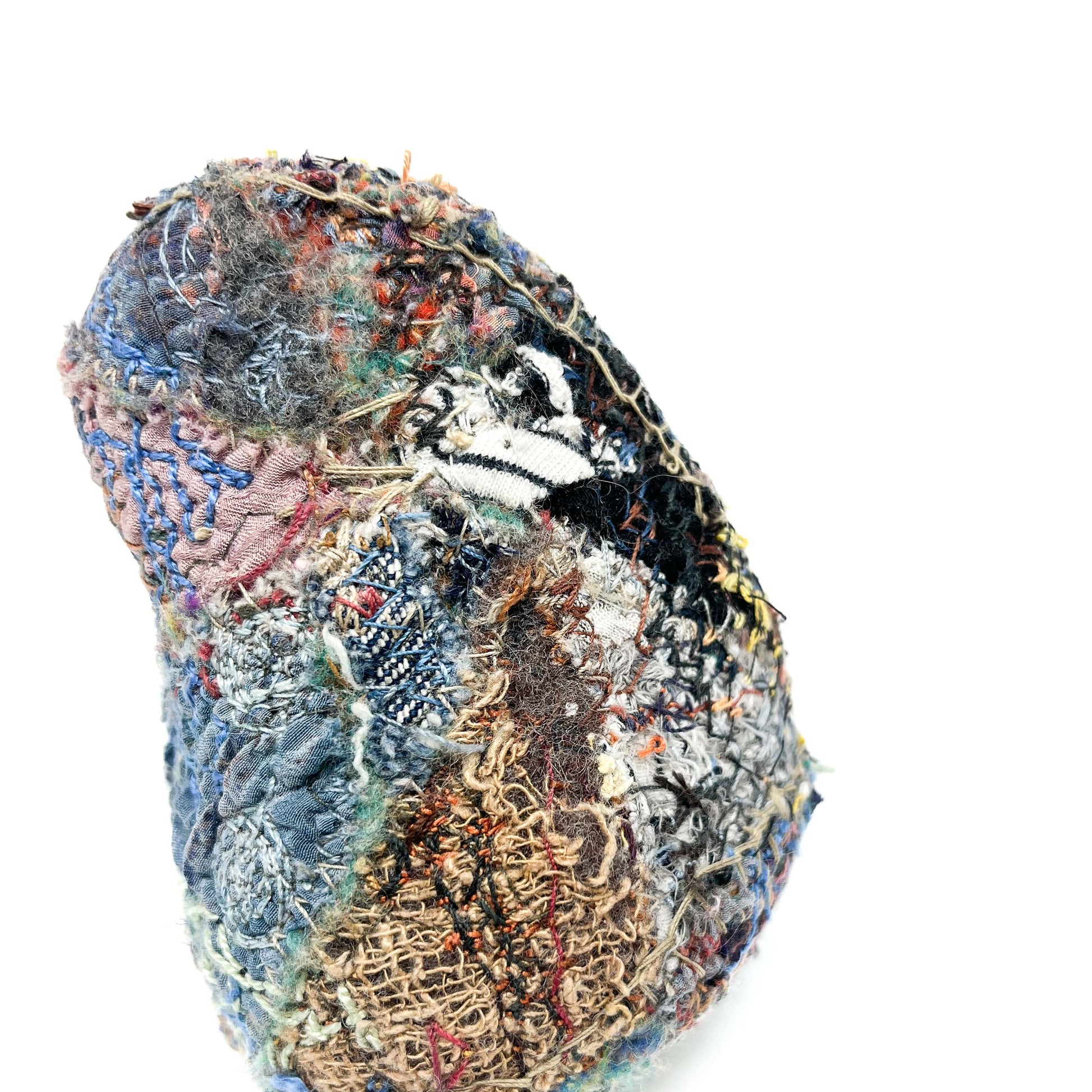 "Embroidered Rock" by Jane Kenyon: A textured stone covered in layers of colorful, stitched fabric and threads.